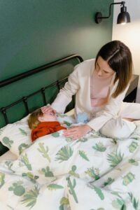 A woman attending to a child lying in bed, showcasing care and concern.